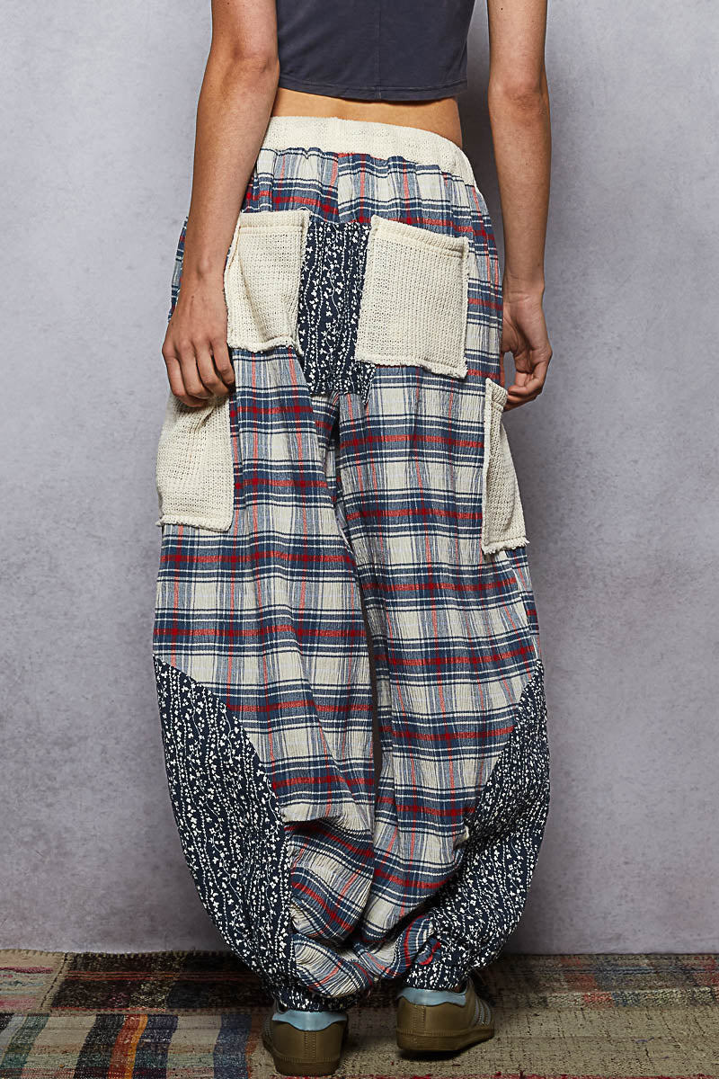 Person wearing plaid harem pants with a plain background