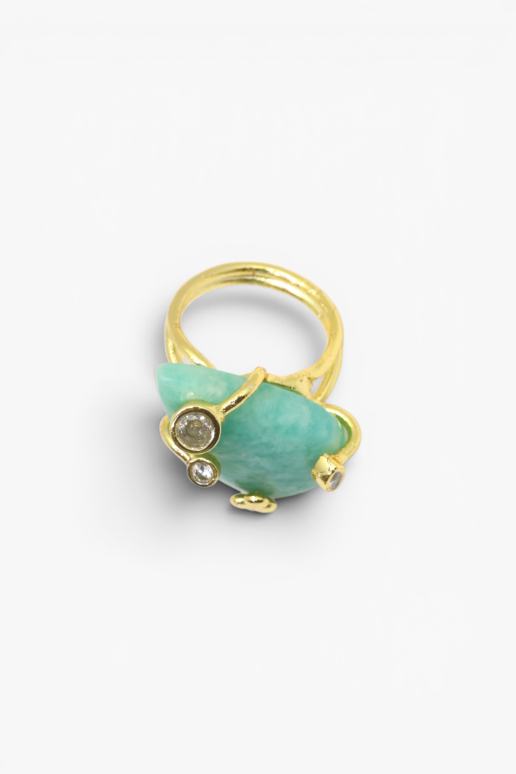 Gold ring with a large green stone and smaller gem on a white background