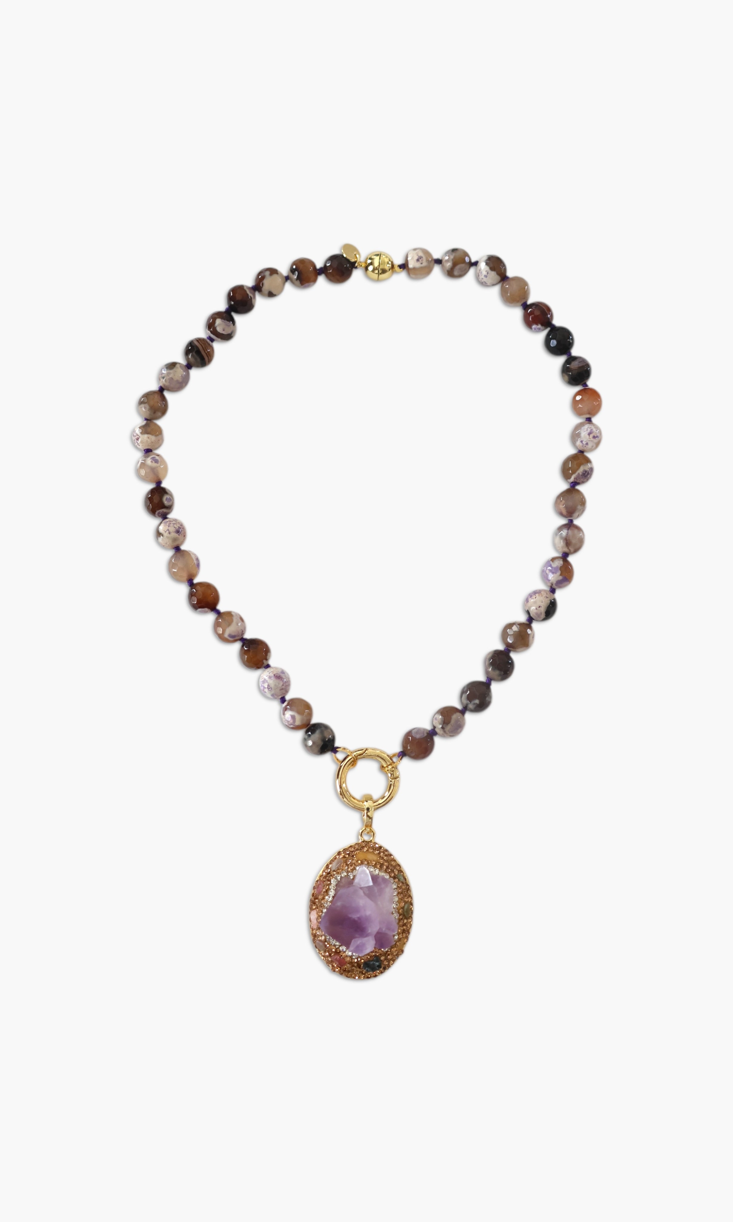 A person wearing multiple necklaces with amethyst stones and gold accents. The necklaces are part of a stack, and the person is holding some of the necklaces, showcasing the jewelry.