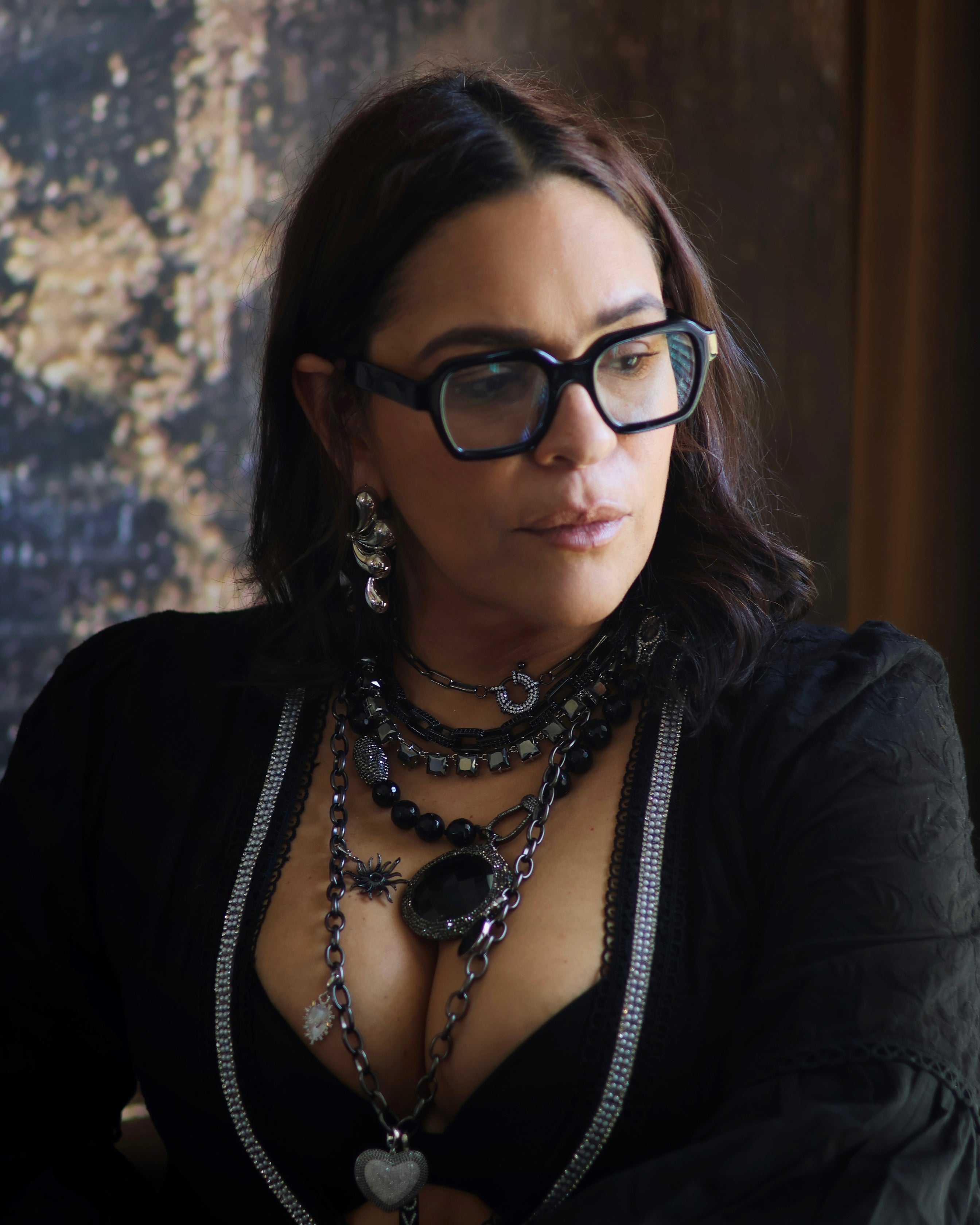 A person wearing multiple necklaces with onyx and gun metal colors.
