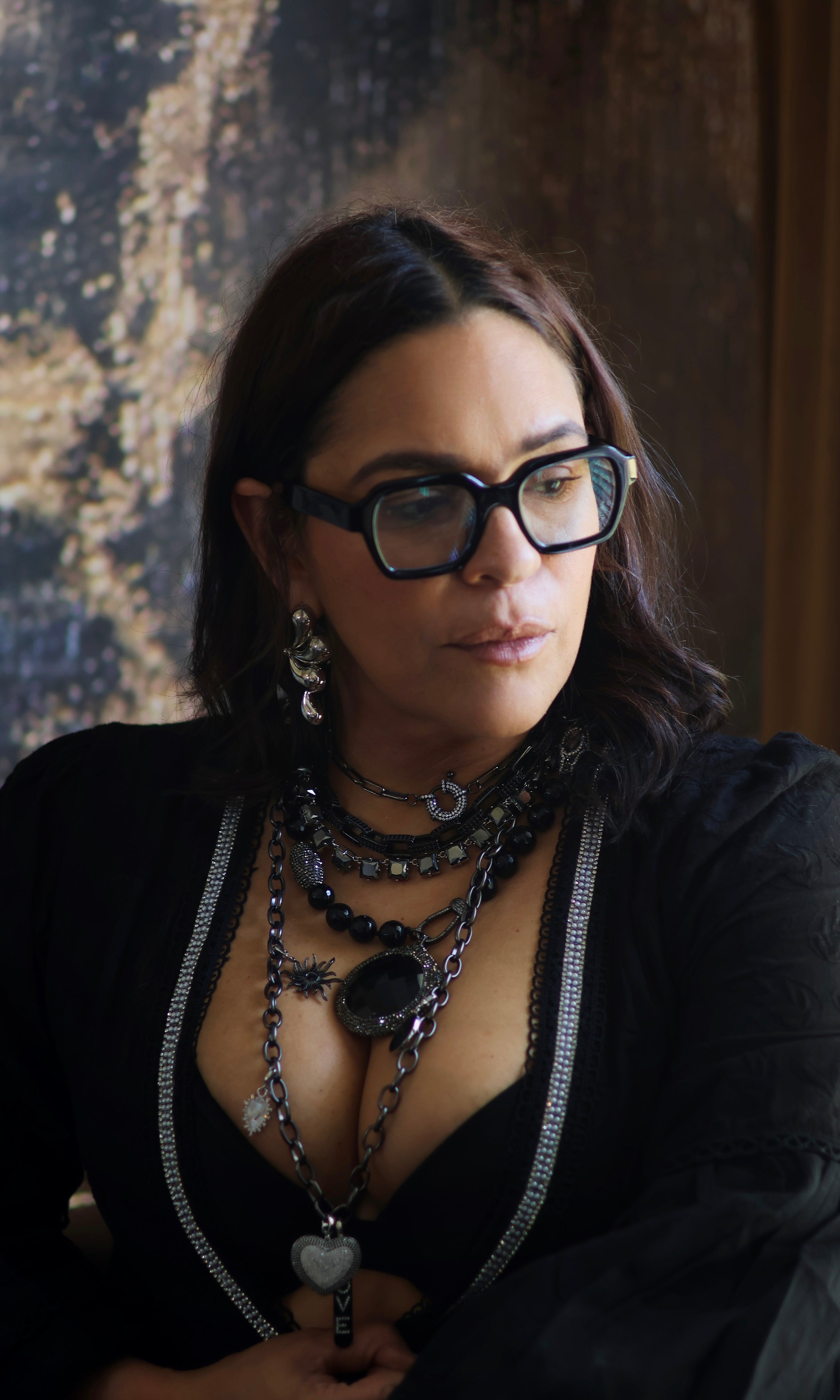 A person wearing multiple necklaces with onyx and gun metal colors.
