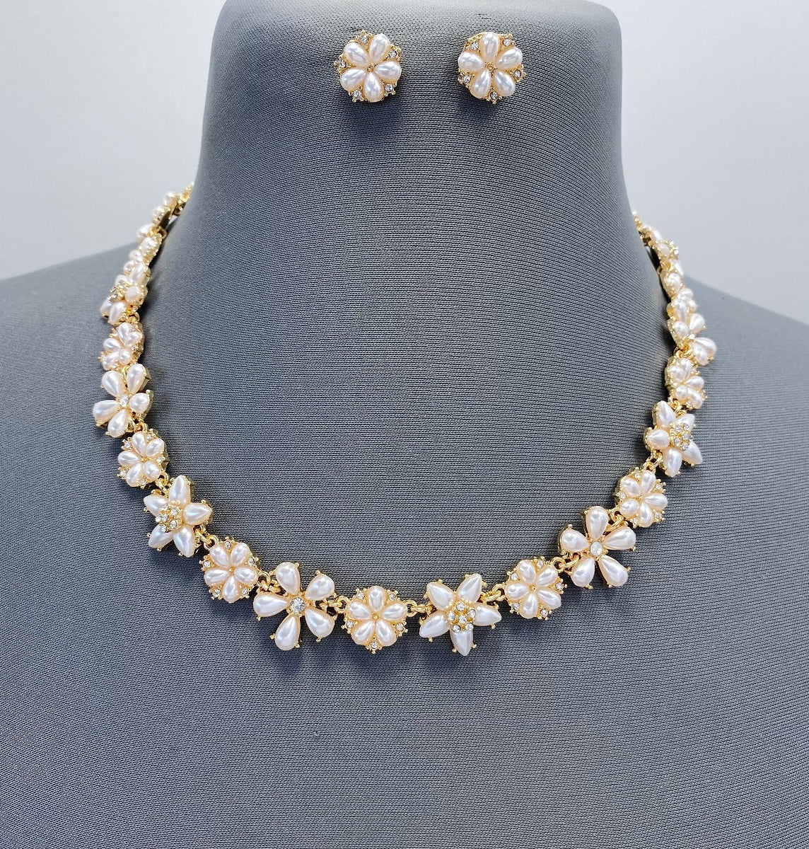 Pearl necklace and earrings set on a mannequin with a gray background