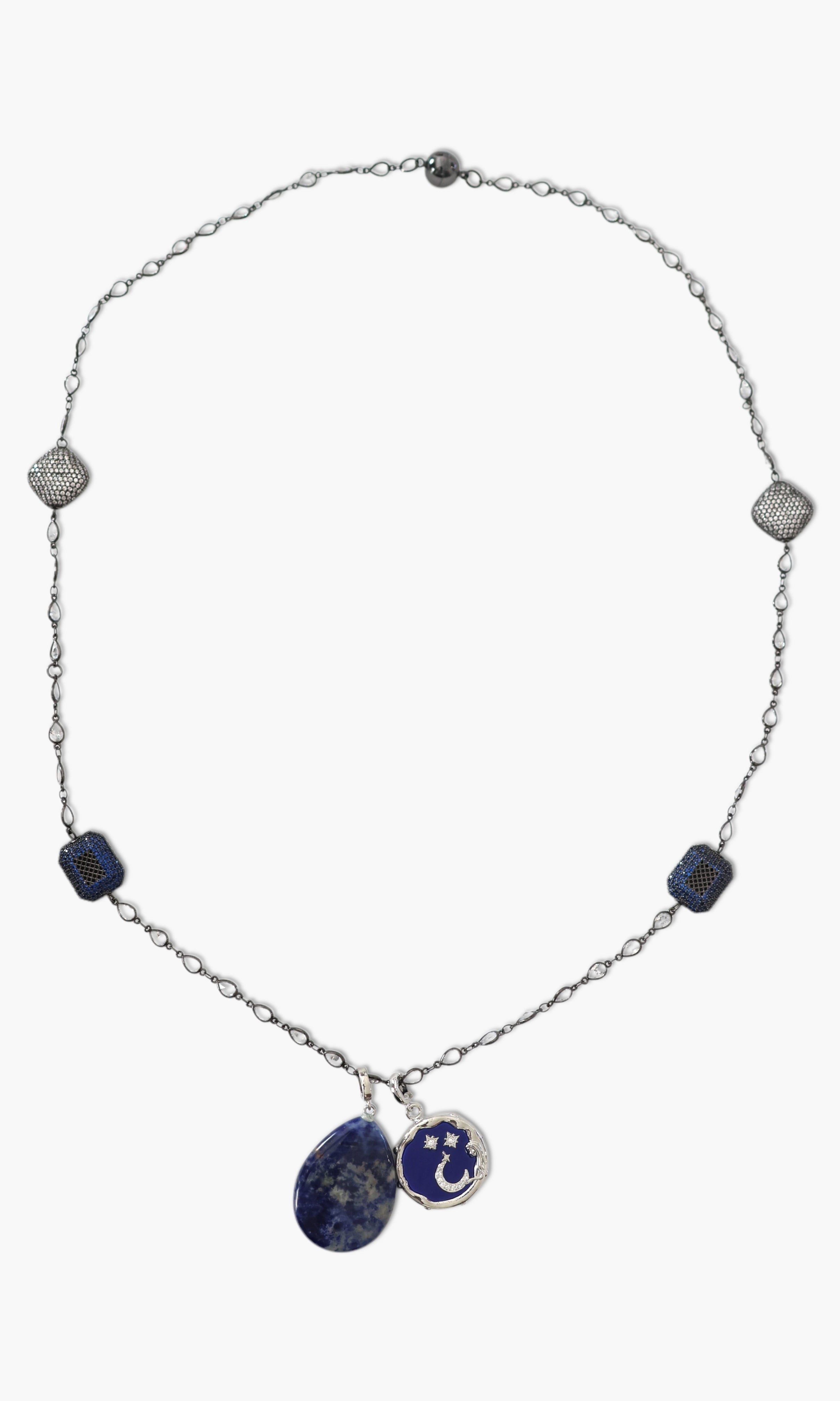 A person wearing a floral shirt and blue jeans, adorned with a stack of blue and gold necklaces featuring lapis lazuli and blue agate.