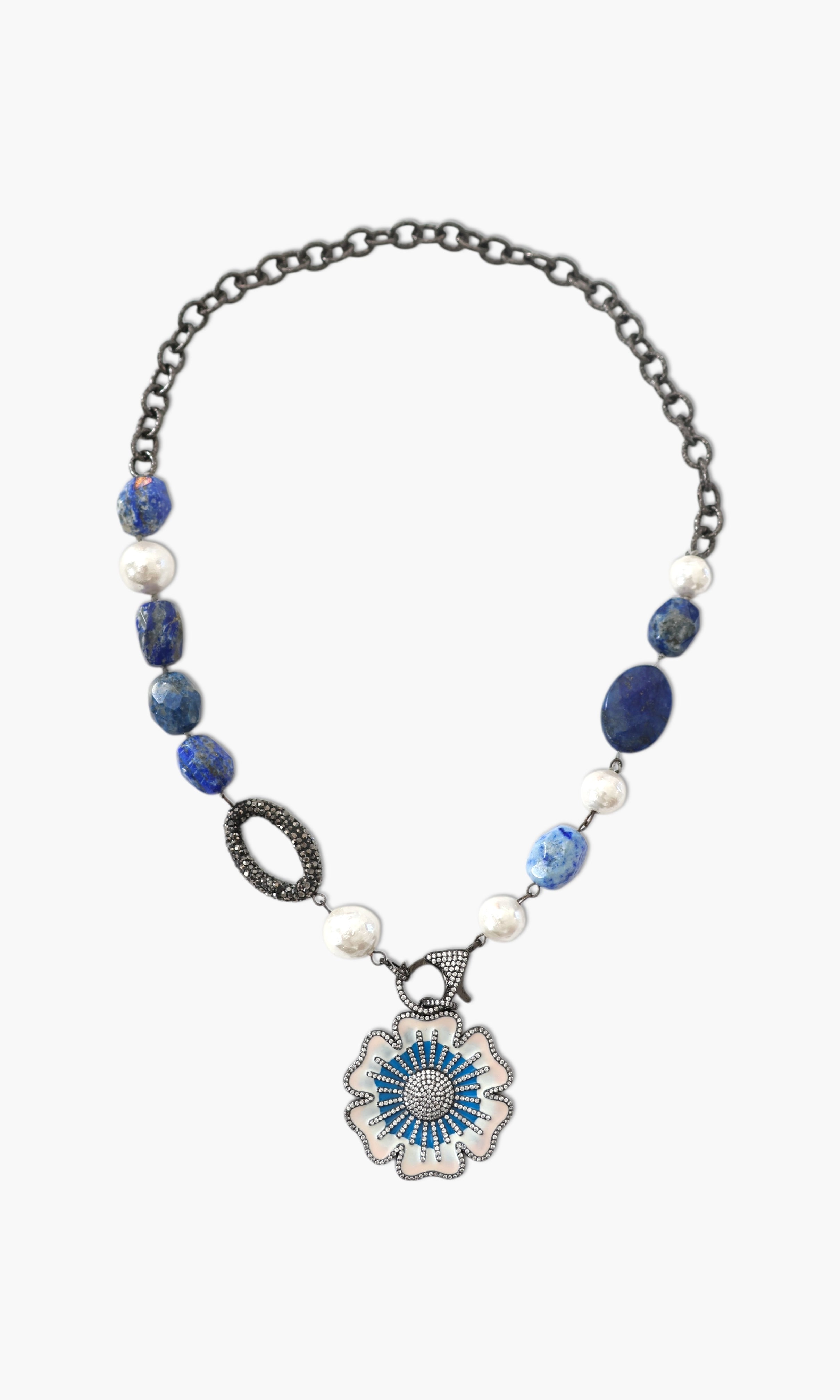 A person wearing a floral shirt and blue jeans, adorned with a stack of blue and gold necklaces featuring lapis lazuli and blue agate.