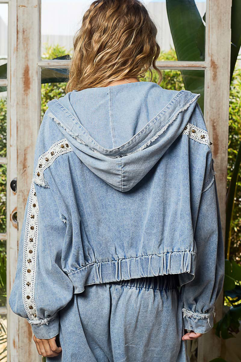 Person wearing a light blue denim outfit with lace details outdoors.