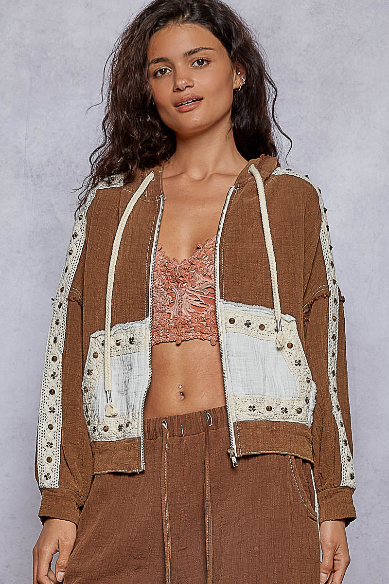 Woman wearing a brown jacket with lace details on a gray background