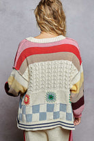 Person wearing a colorful, patterned sweater against a gray background