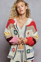 Woman wearing a colorful, patterned cardigan against a gray background