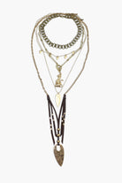 A layered brass necklace with various geometric shapes and a prominent arrowhead design.