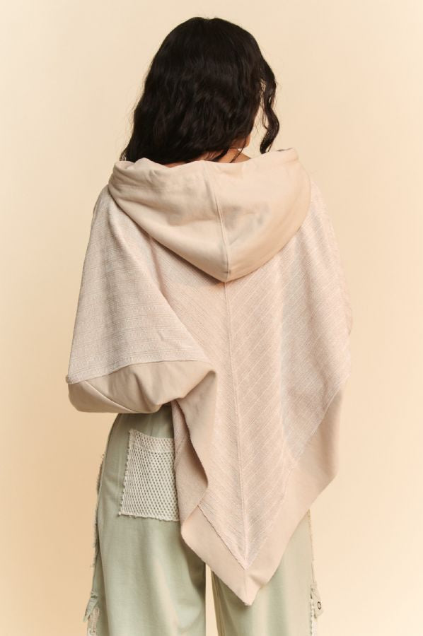 Person wearing a light-colored shawl over shoulders against a beige background