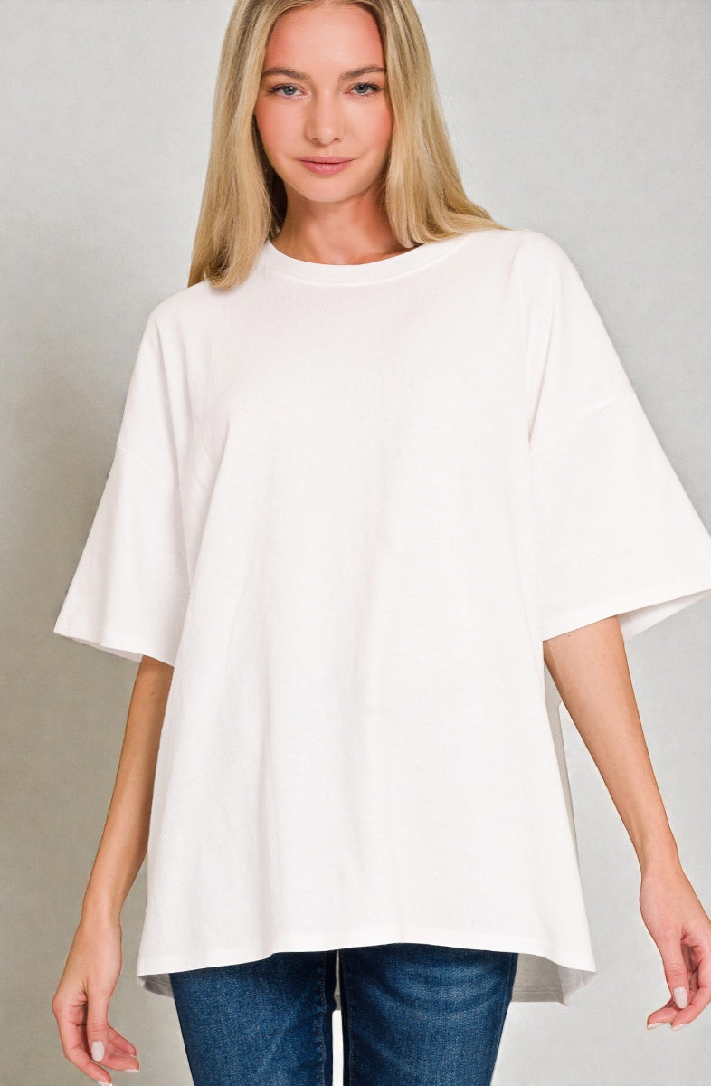 Woman wearing a white oversized top and blue jeans on a gray background