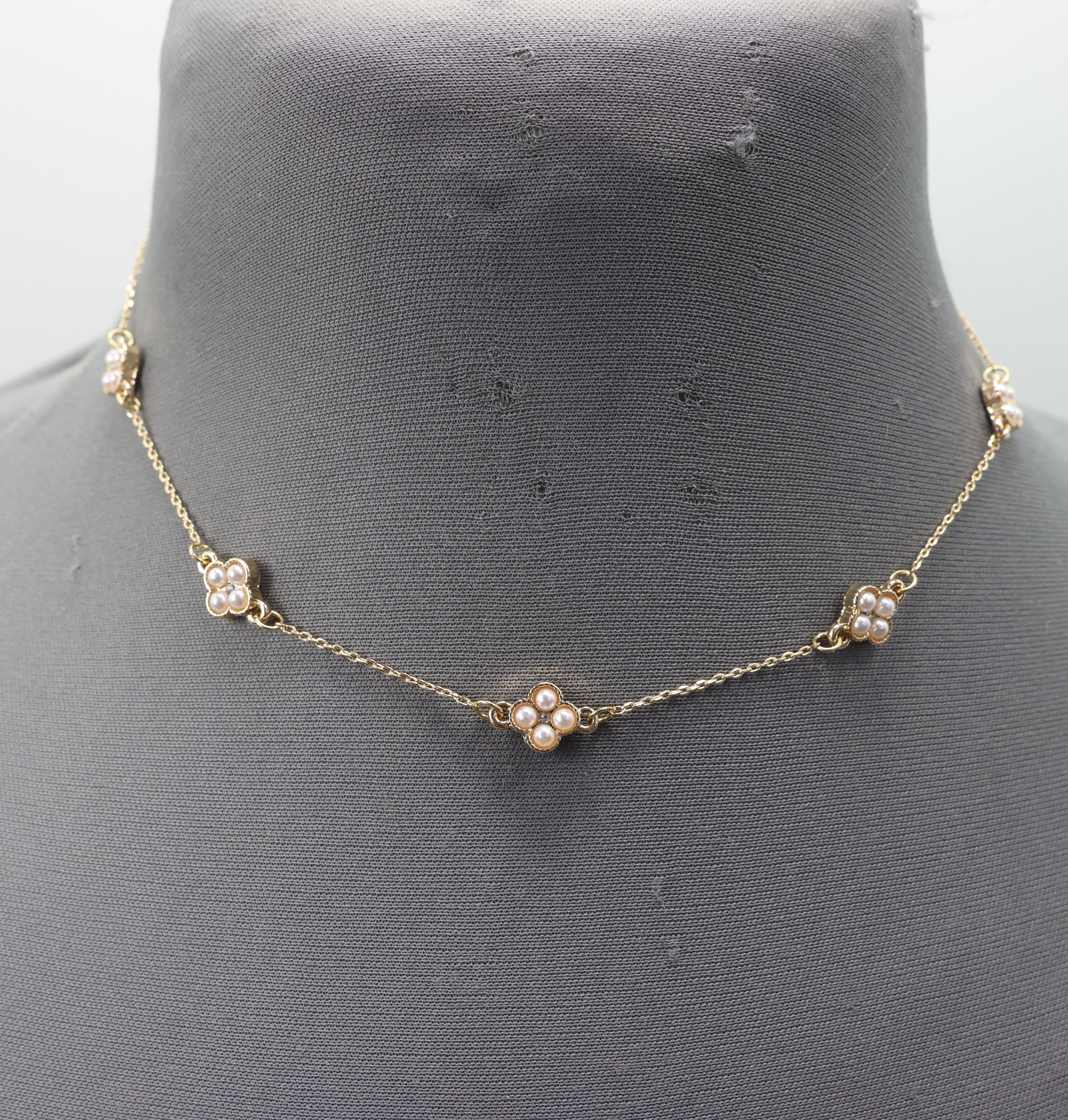 Gold necklace with pearl-like beads on a mannequin bust.