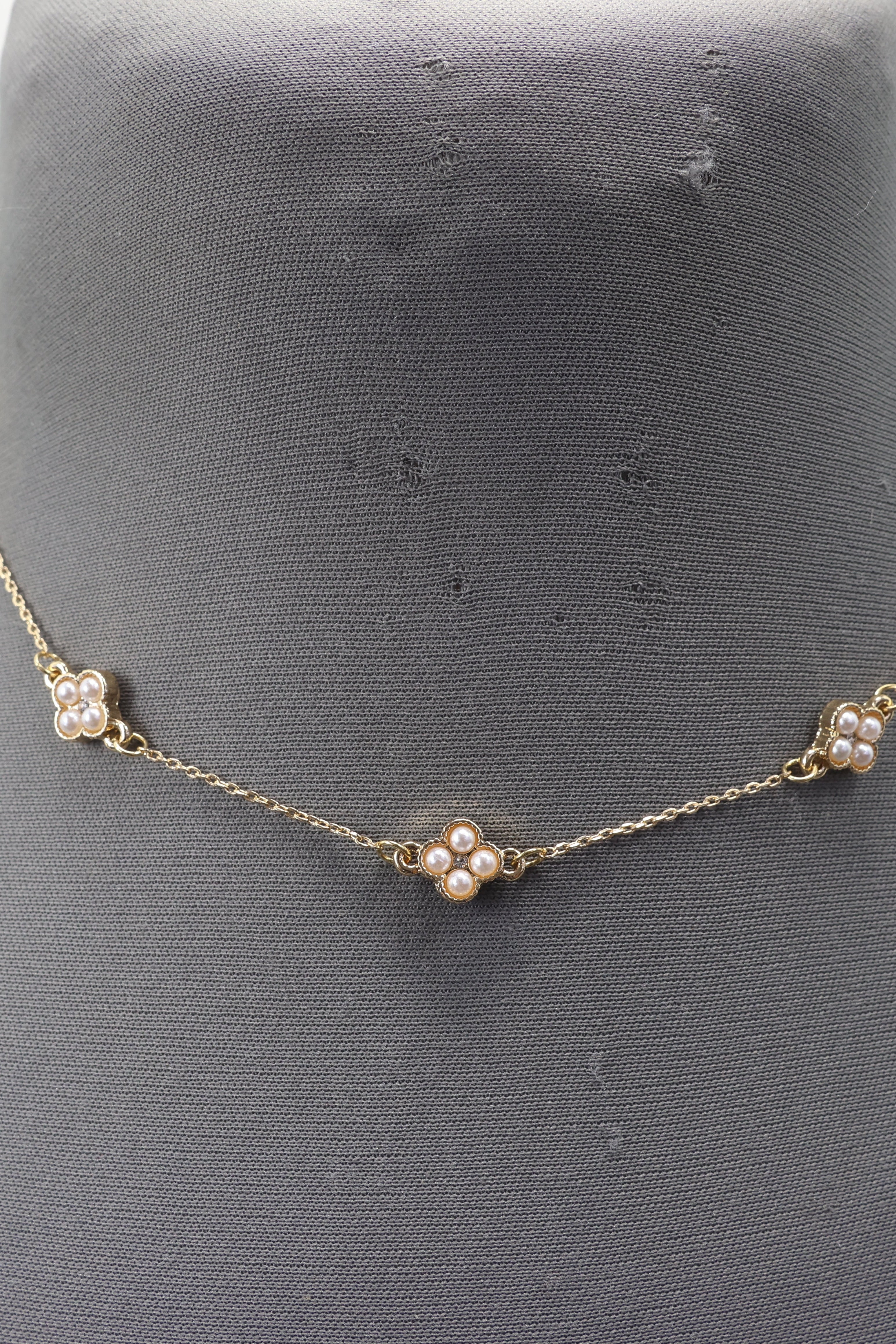 Gold necklace with pearl-like beads on a mannequin bust.