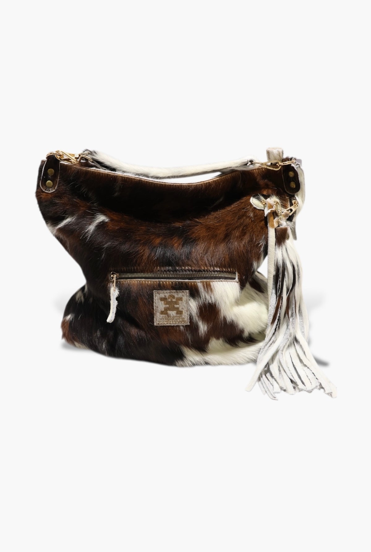 Brown and white cowhide handbag with tassel on a white background