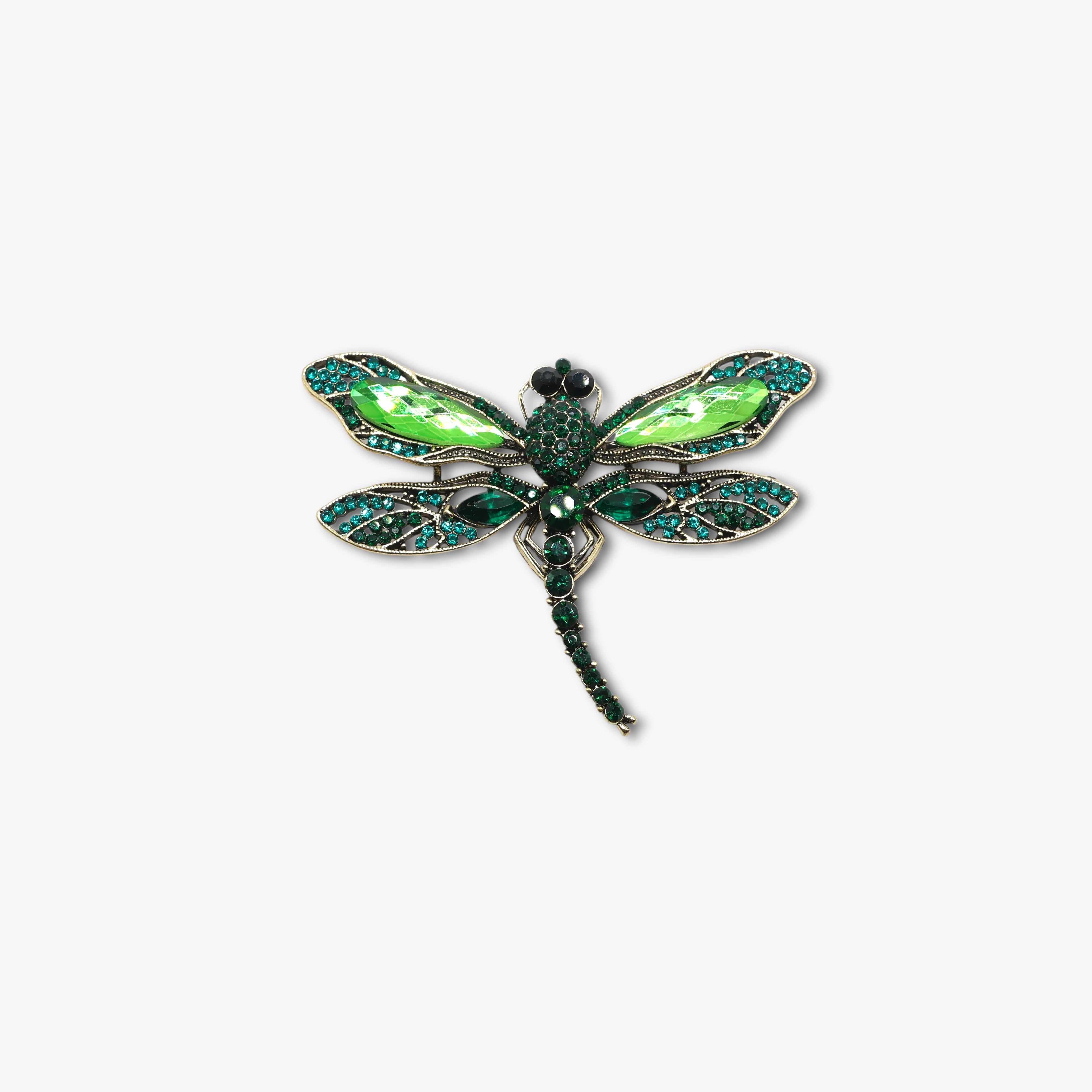 Green dragonfly-shaped brooch with gemstones on a white background