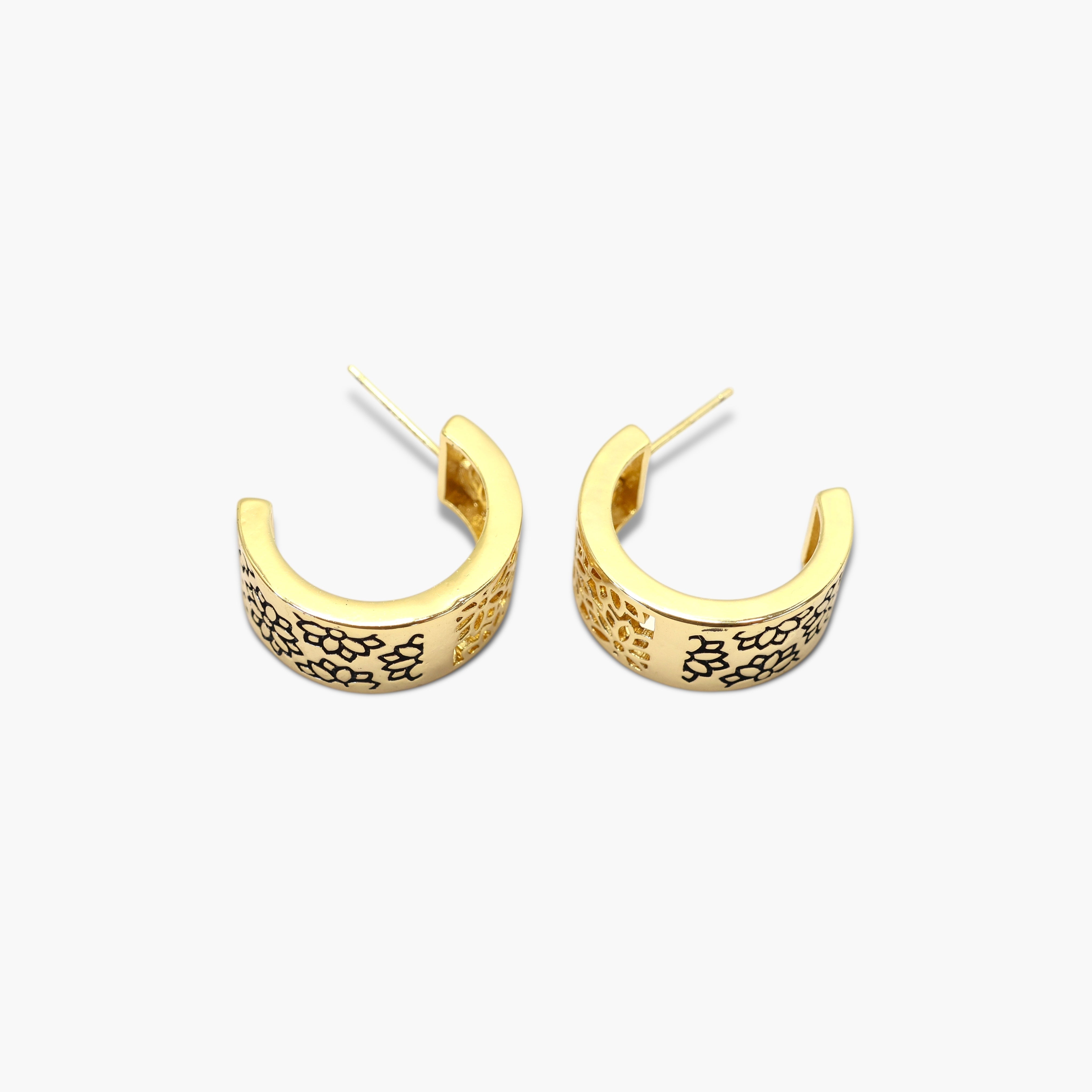 A pair of gold-colored hoop earrings with a floral pattern on the hoop.