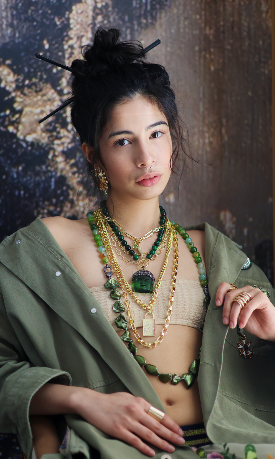 A person wearing multiple necklaces with green jade stones and gold accents. The necklaces are part of a stack, with some featuring intricate gold designs and others with plain green jade.