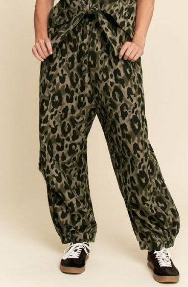 Leopard print pants worn by a person on a beige background