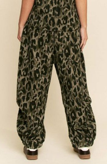 Leopard print pants worn by a person on a beige background