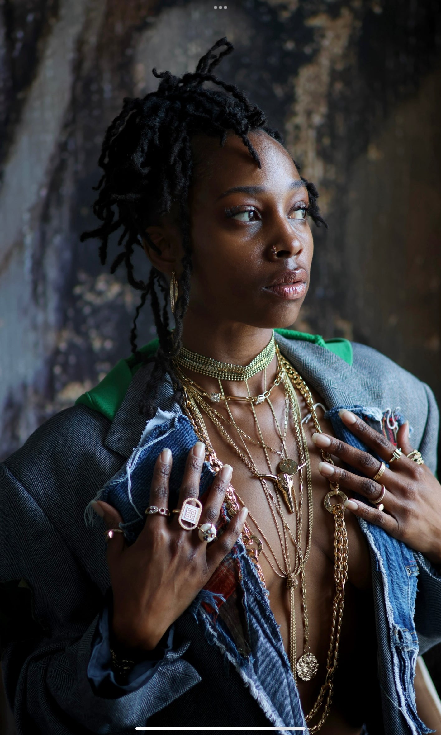 A person showcasing a long horn necklace with multiple chains and separate pieces that flow together into one piece. The setting appears to be indoors with a rustic backdrop.