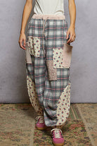 Person wearing plaid and patchwork pants with a plain background