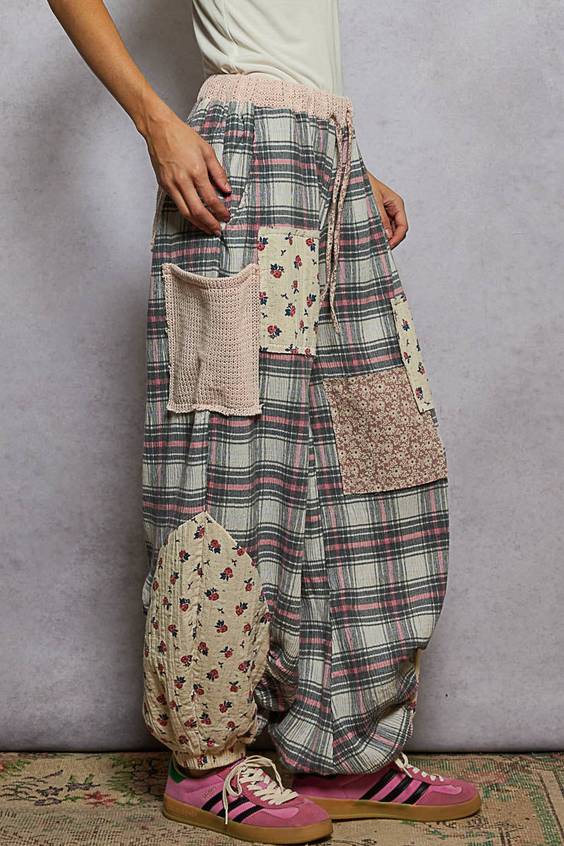 Person wearing plaid pants with patchwork details against a gray background