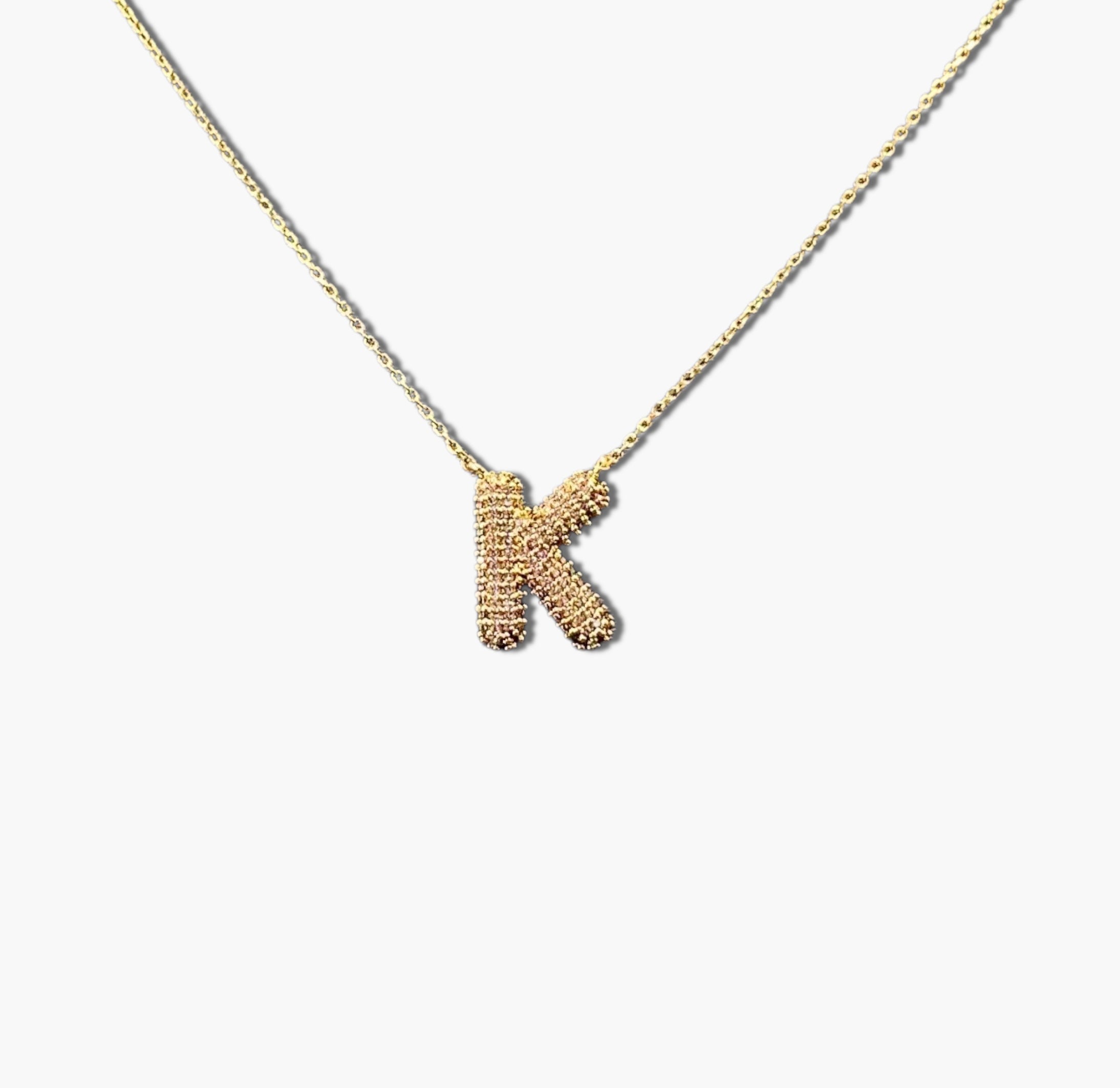 A gold-plated letter necklace with a pleated design on the pendant.