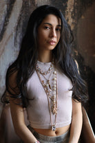 A person wearing a white top and pearl star fish necklace with multiple layers and geometric shapes.