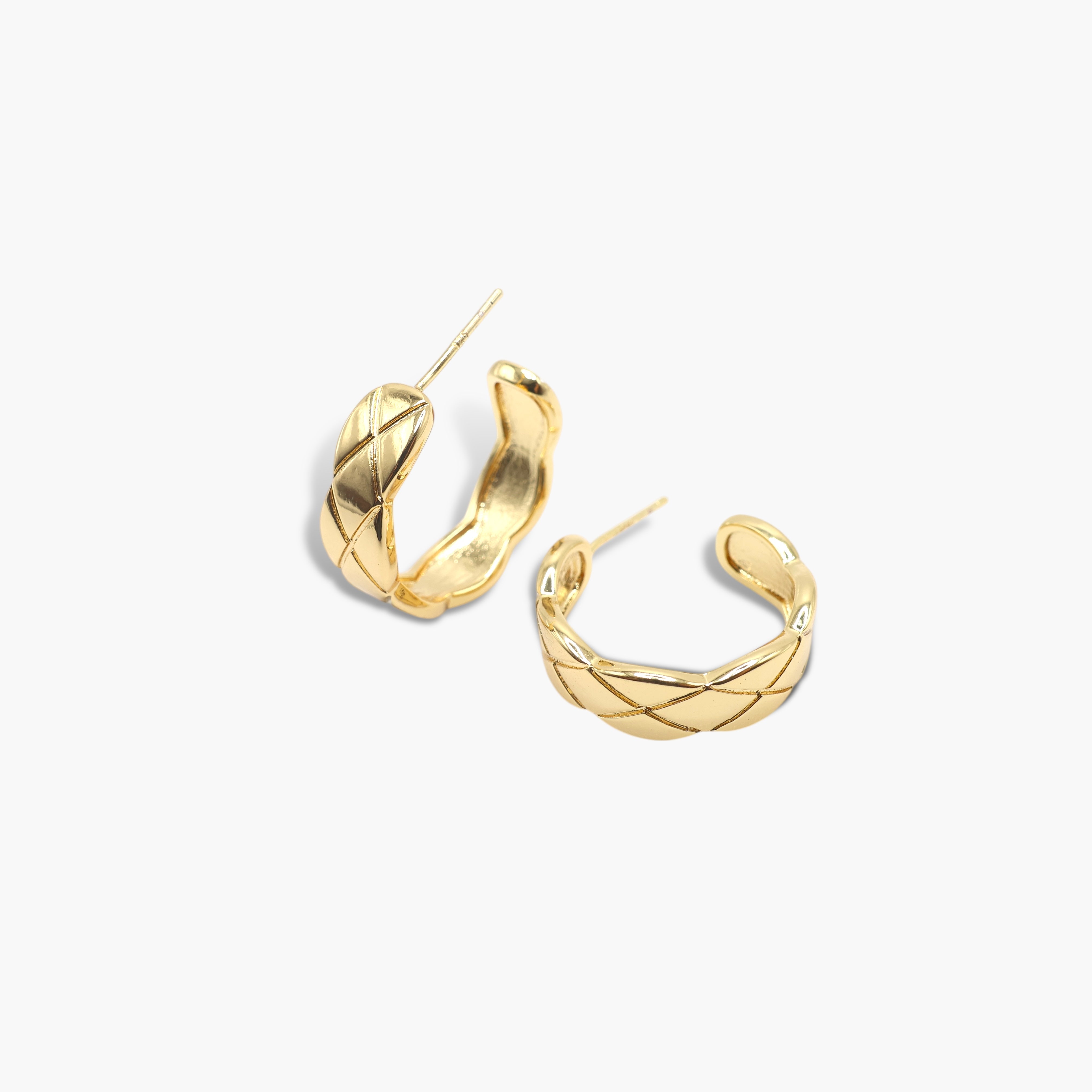 A pair of silver-colored mini hoop earrings with a textured surface, displayed against a white background.