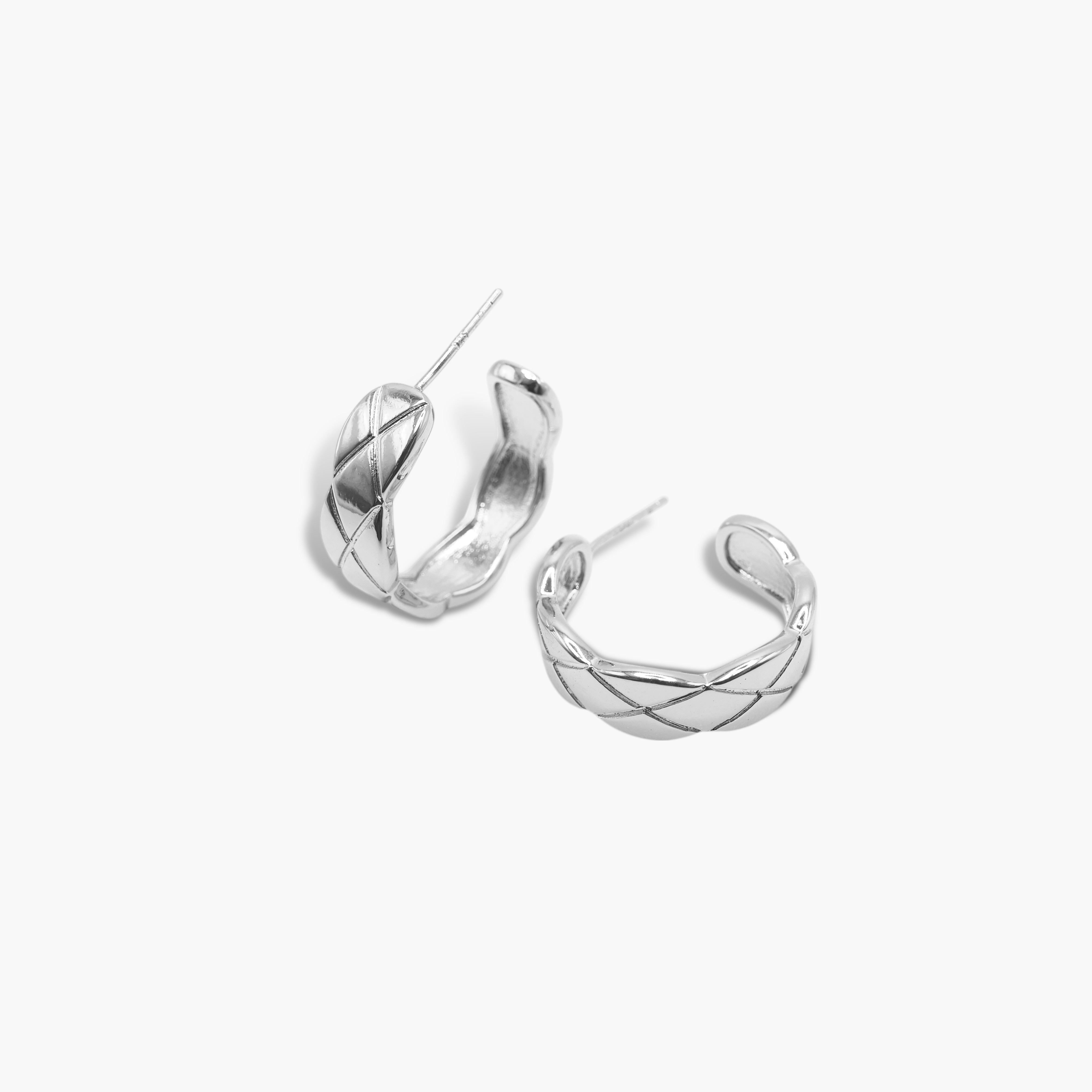 A pair of silver-colored mini hoop earrings with a textured surface, displayed against a white background.