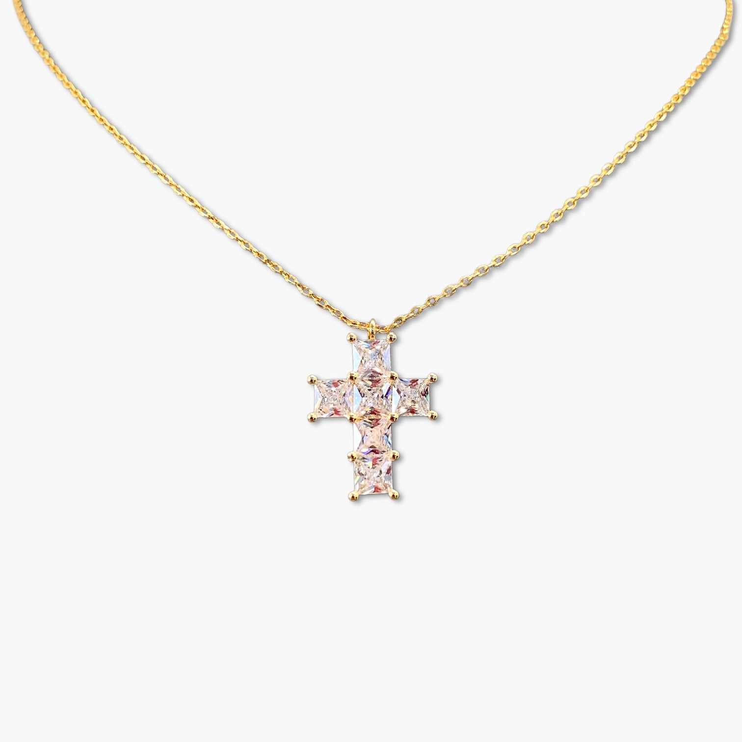 A gold-colored cross necklace with cubic zirconia stones on a white background.