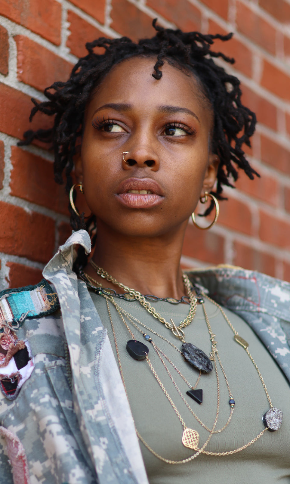 A person wearing multiple necklaces with varying designs and lengths, layered to create a flowing stack effect.