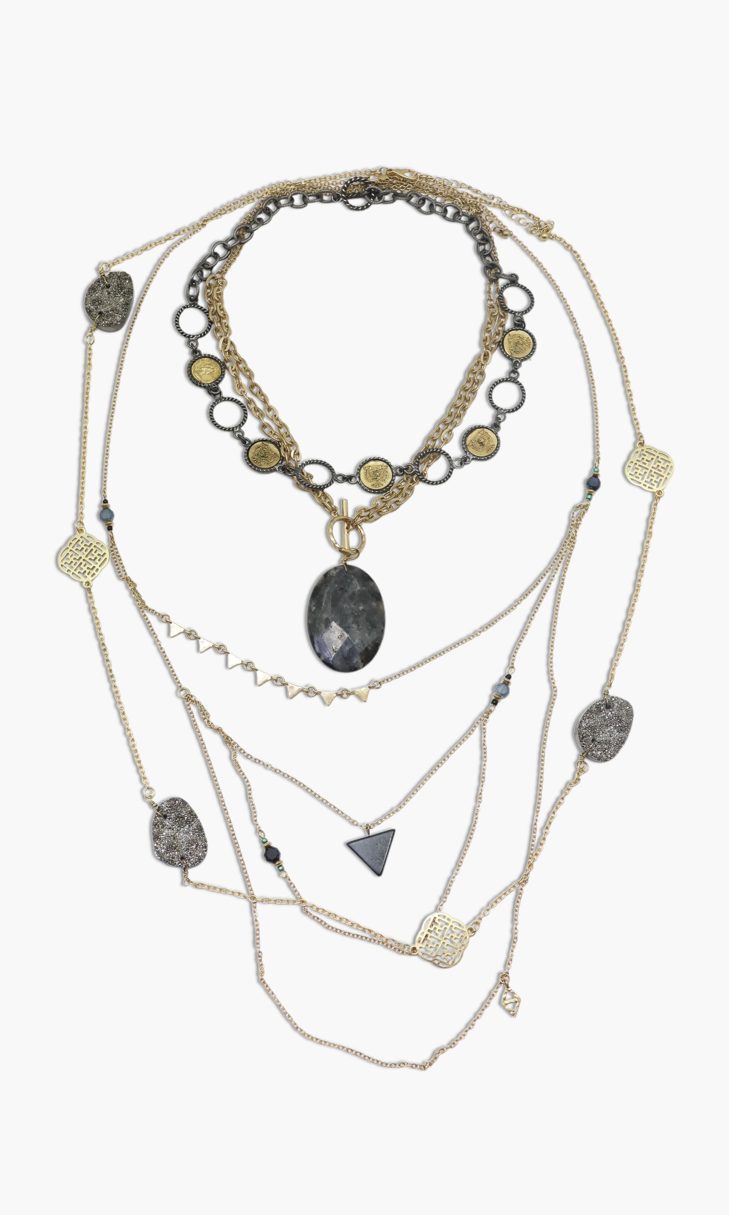 A layered necklace set with a variety of geometric pendants and a prominent central stone pendant, predominantly in shades of silver and gold.