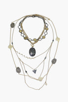 A layered necklace set with a variety of geometric pendants and a prominent central stone pendant, predominantly in shades of silver and gold.