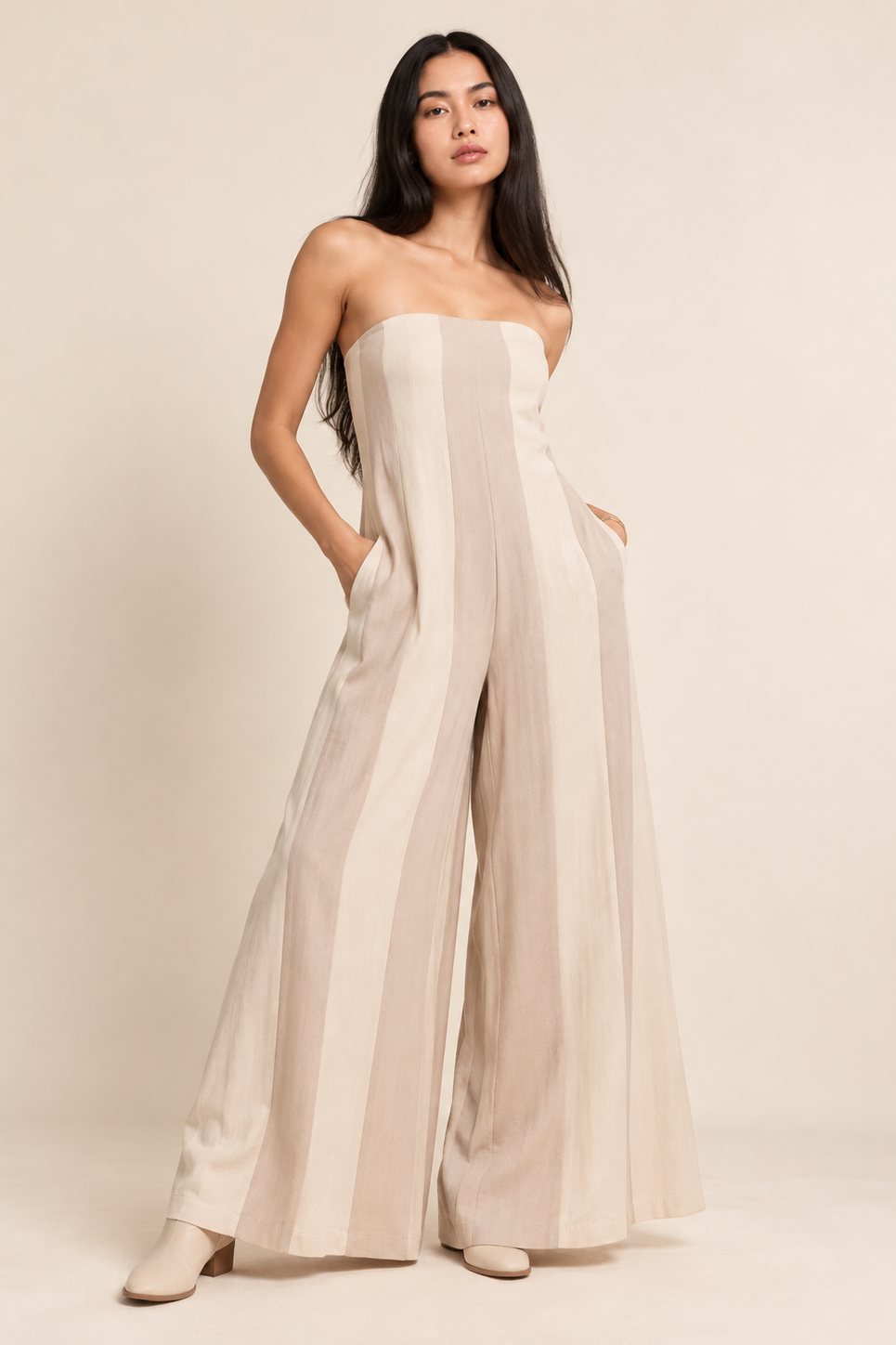 Model wearing a strapless wide-leg jumpsuit with vertical stripe detailing and side pockets