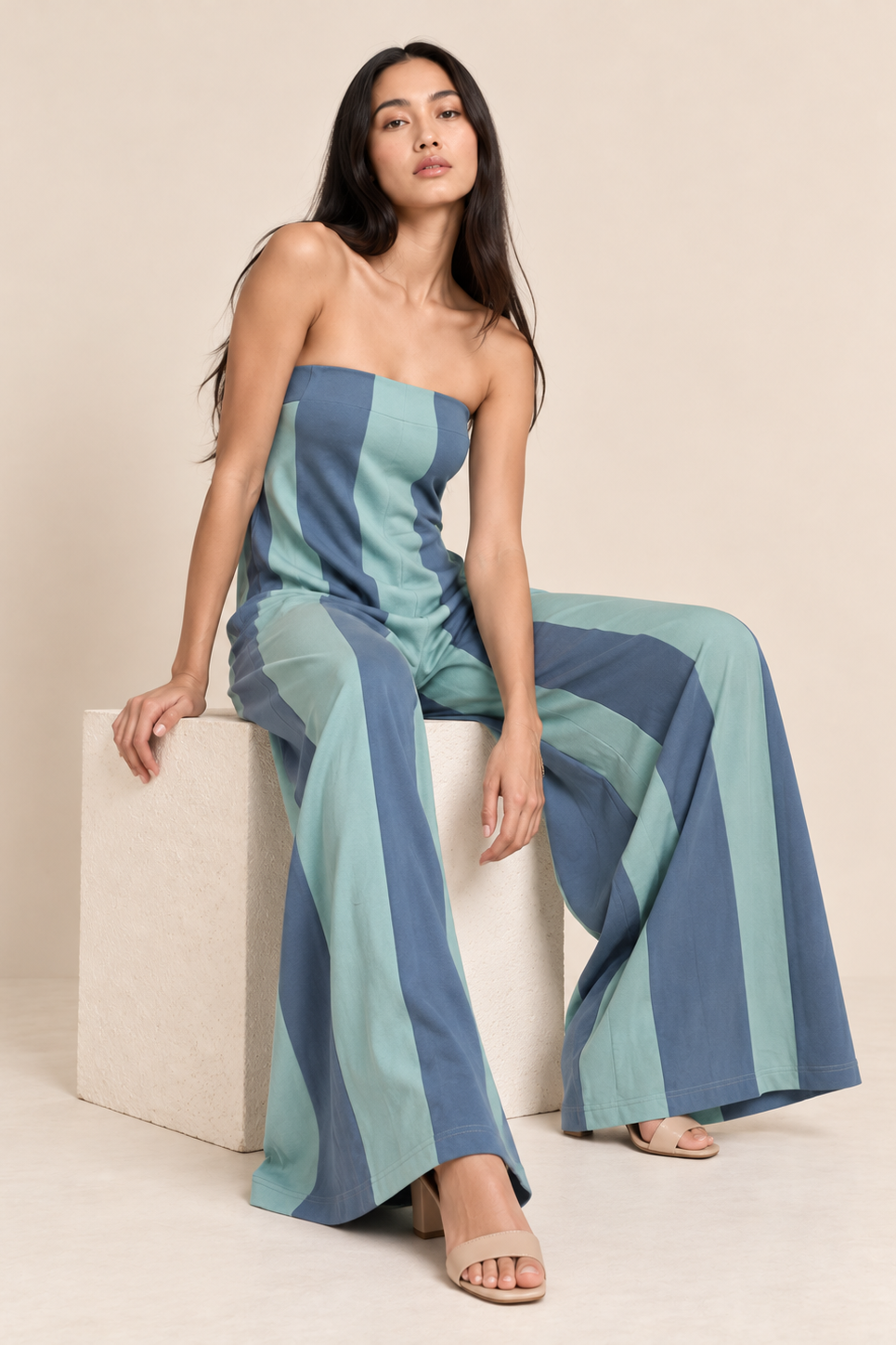 Model wearing a strapless wide-leg jumpsuit with vertical stripe detailing and side pockets