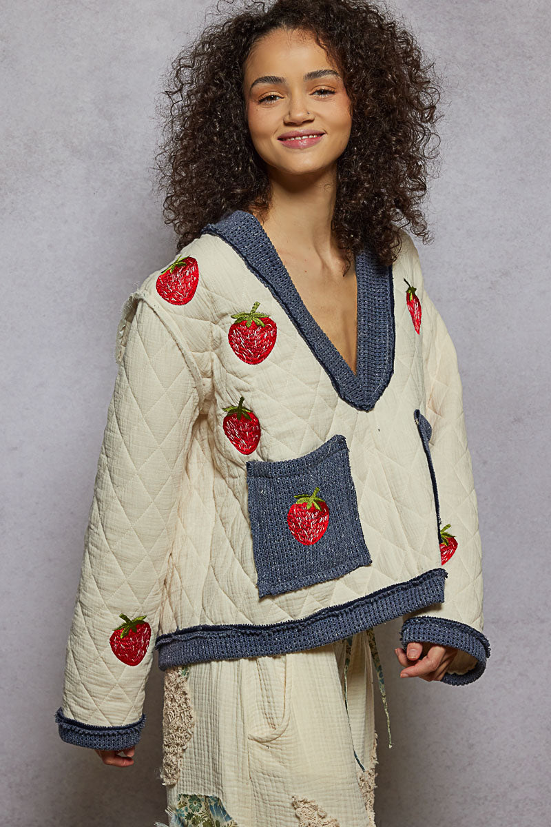 Woman wearing a quilted jacket with strawberry designs on a gray background