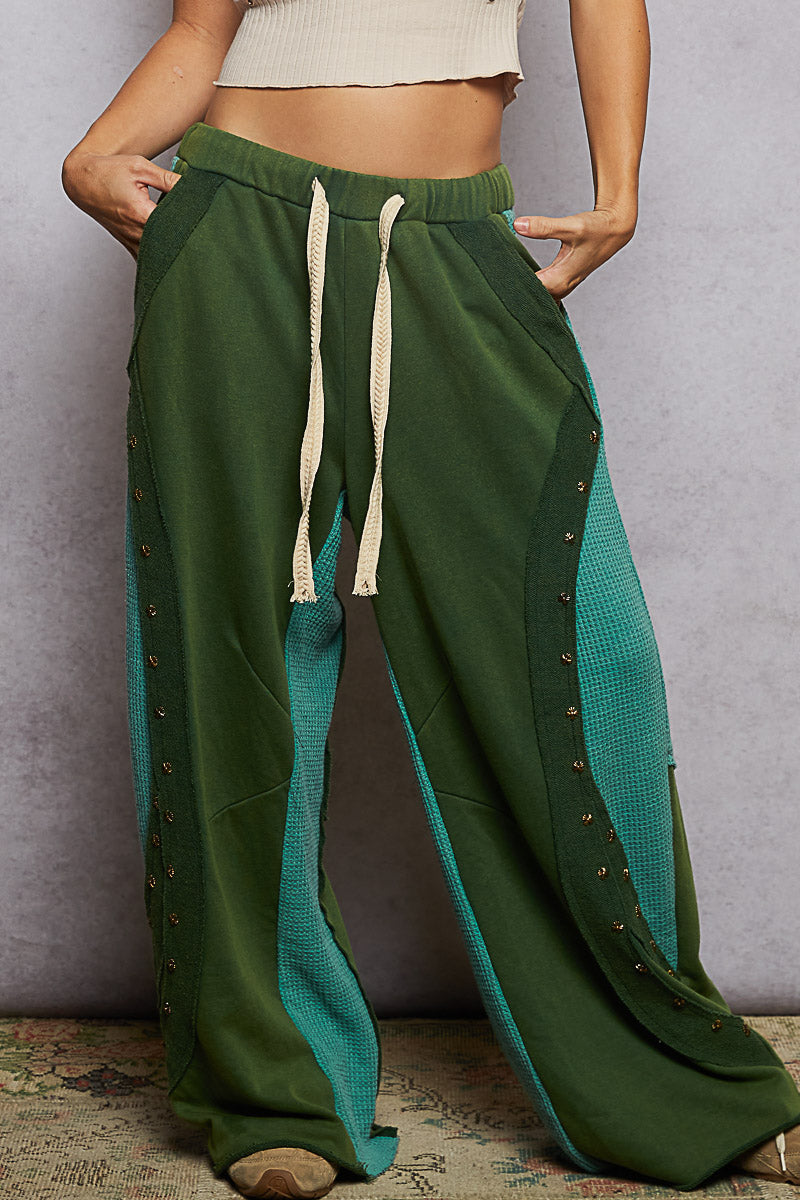 Green wide-leg pants with a textured pattern on a neutral background