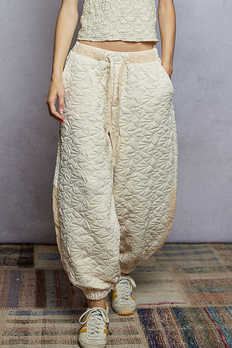 Person wearing textured beige pants and a matching top on a plain background