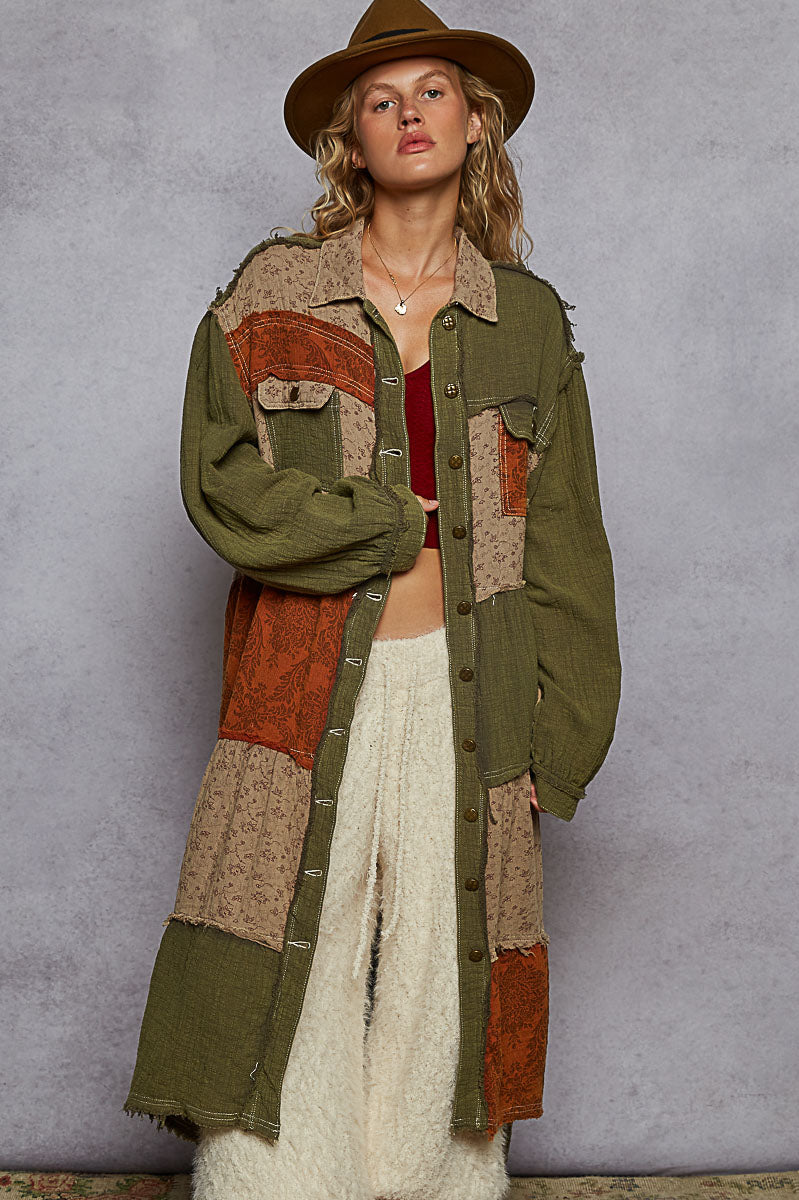 Person wearing a patchwork jacket with earthy tones against a gray background