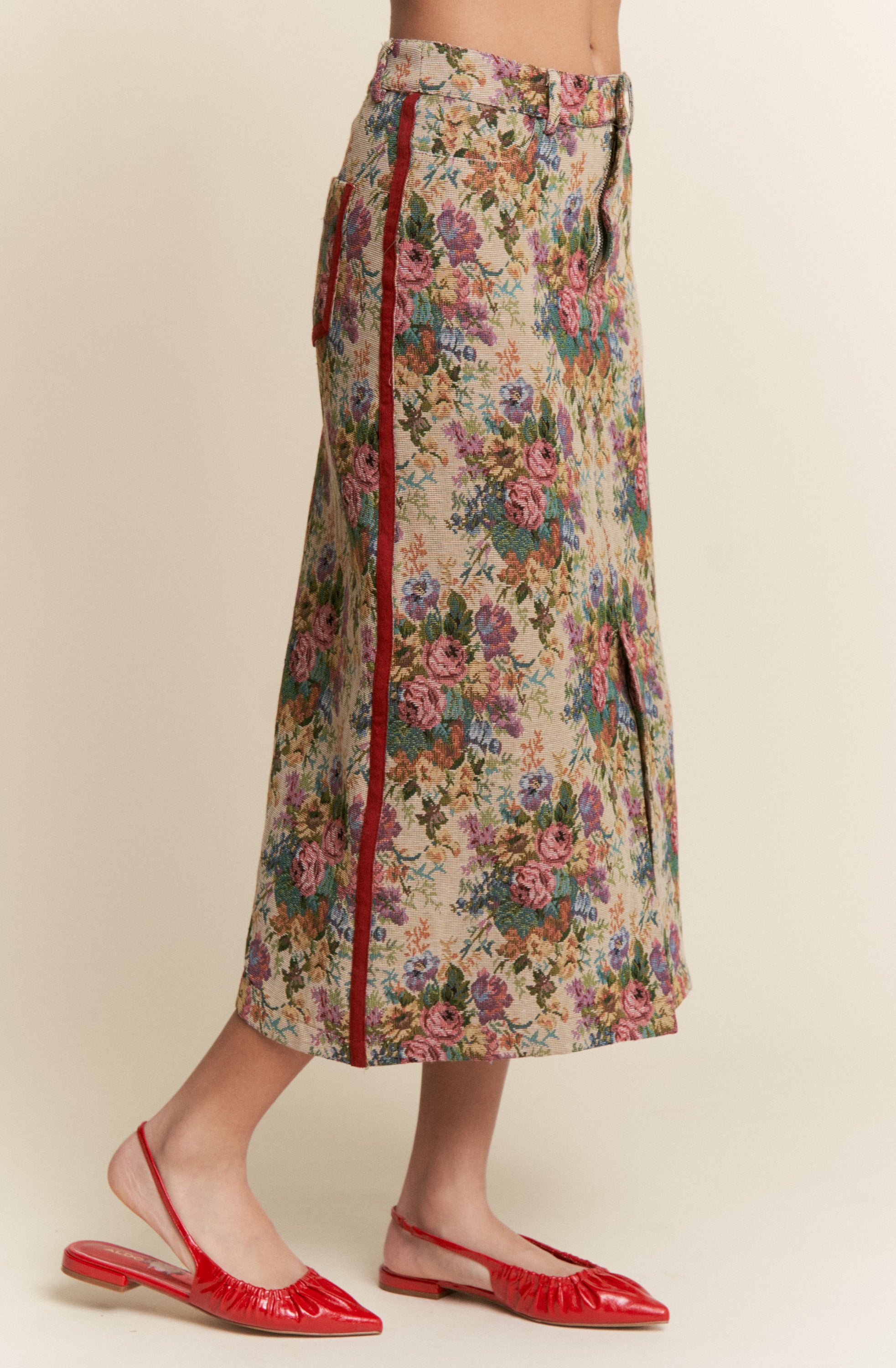 Floral skirt with red zipper and red shoes on a beige background