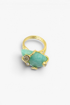 Gold ring with a large green stone and smaller gem on a white background