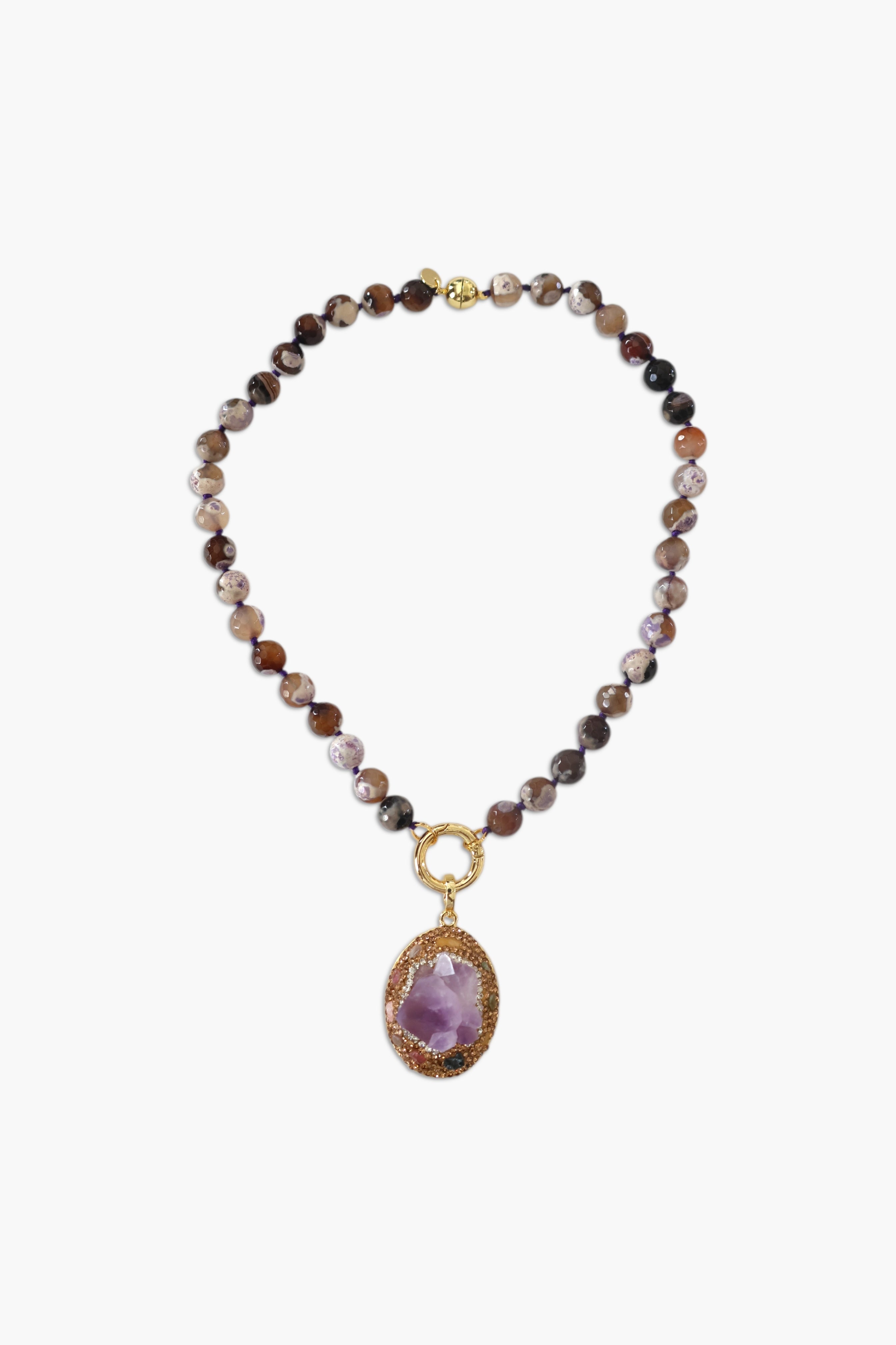 A person wearing multiple necklaces with amethyst stones and gold accents. The necklaces are part of a stack, and the person is holding some of the necklaces, showcasing the jewelry.