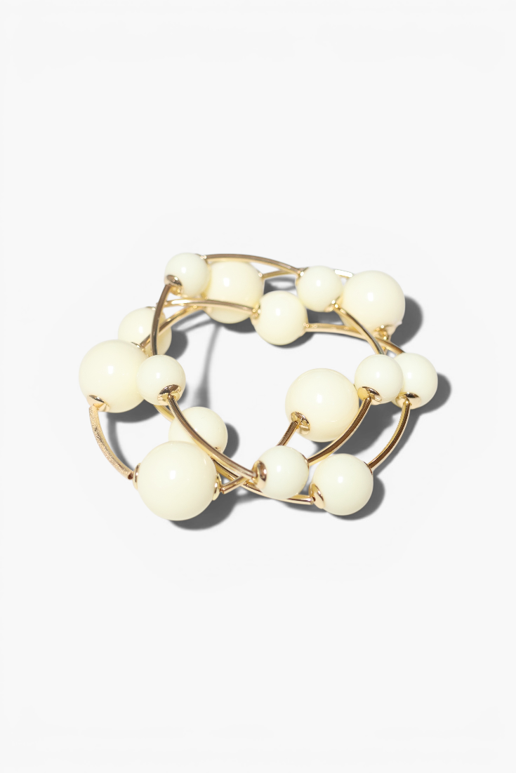 Gold ring with white beads on a light beige background