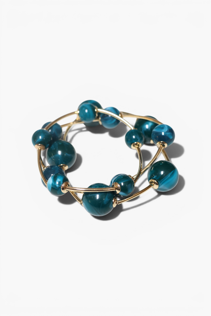 Teal beaded ring with gold wire on a white background