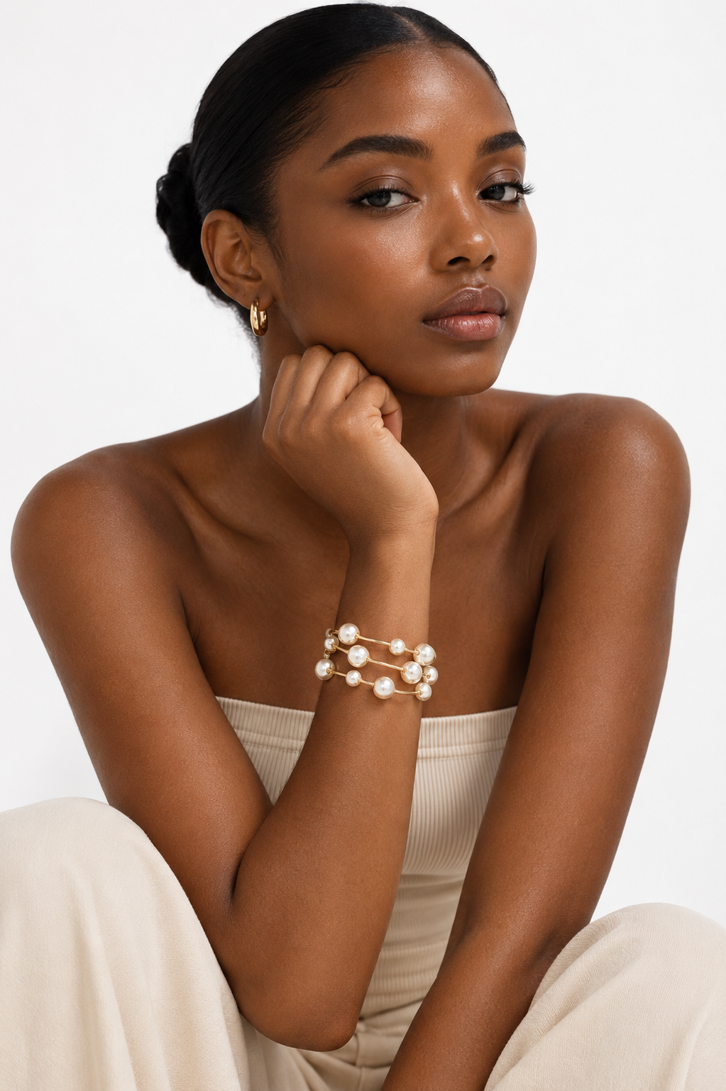 Woman wearing pearl bracelet and earrings on a white background