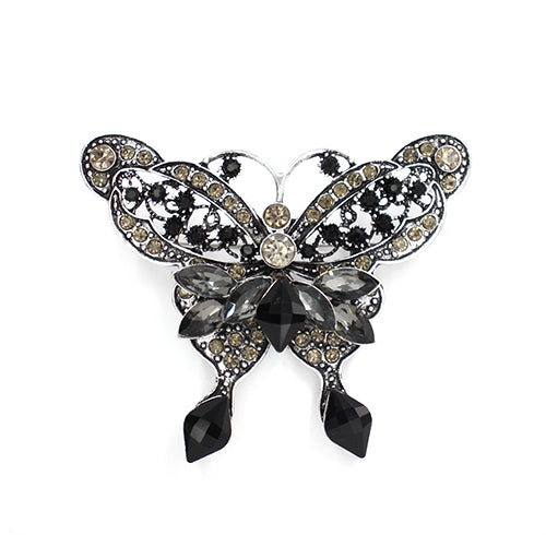 Butterfly-shaped brooch with gemstones on a white background