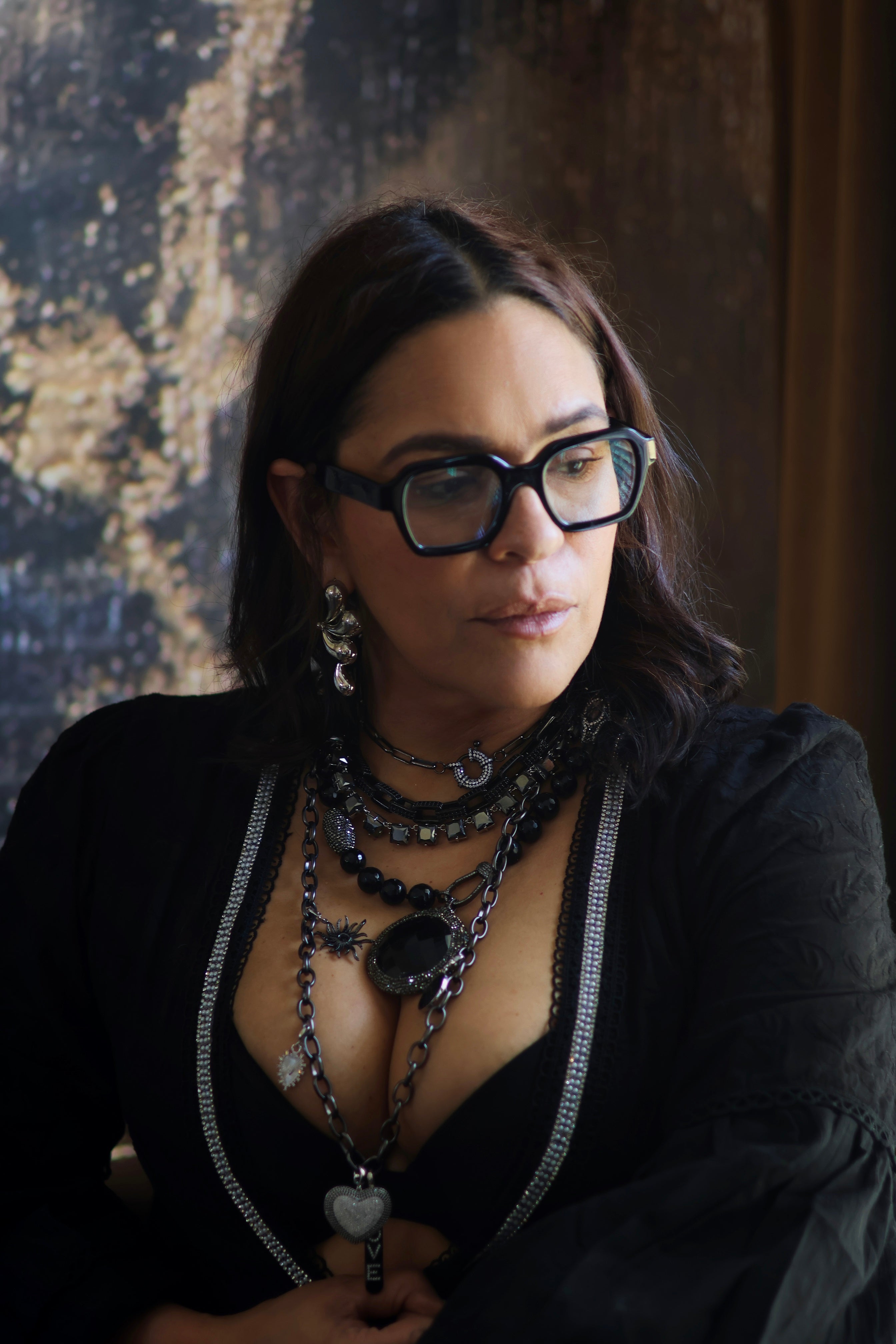 A person wearing multiple necklaces with onyx and gun metal colors.