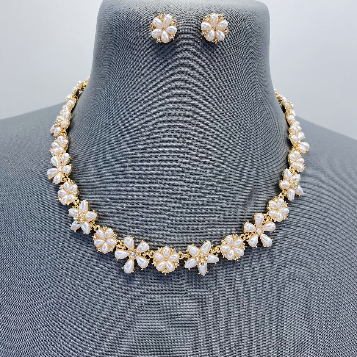 Pearl necklace and earrings set on a mannequin with a gray background