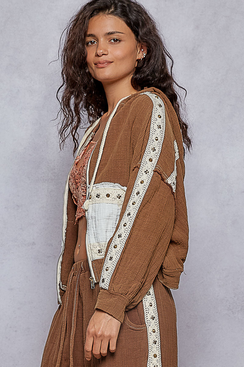 Woman wearing a brown outfit with lace details against a gray background